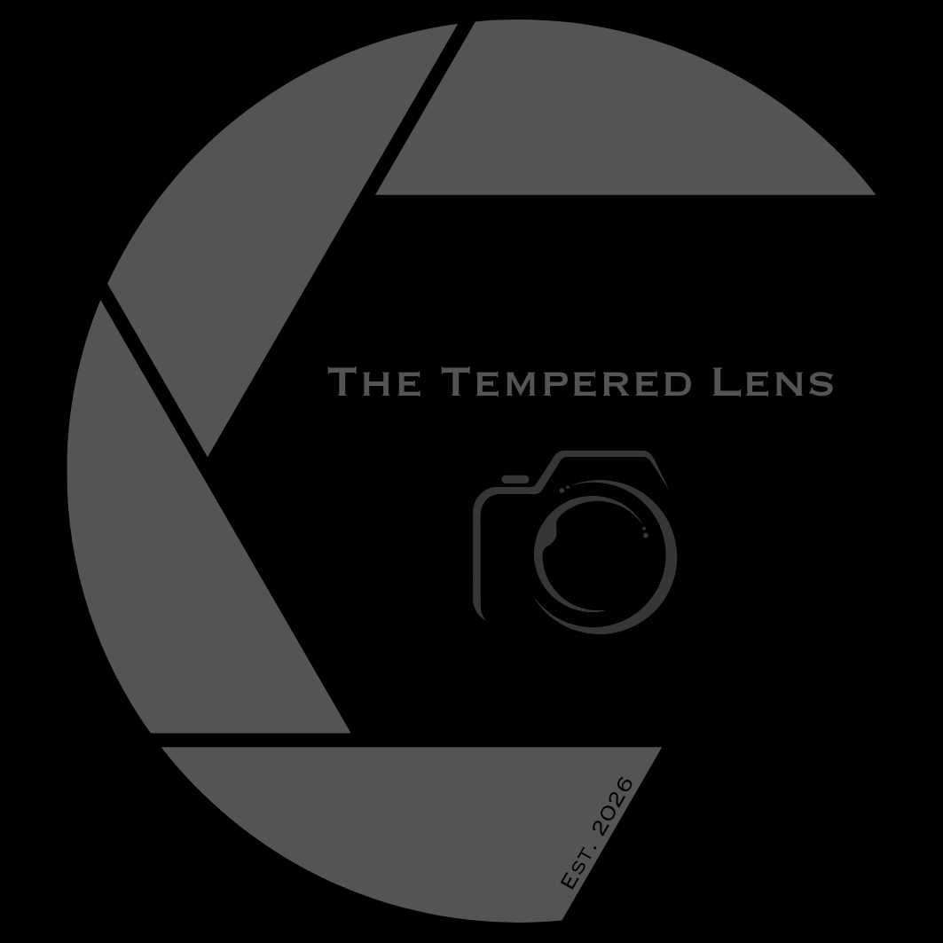 The Tempered Lens logo, featuring an aperture and camera, established 2026